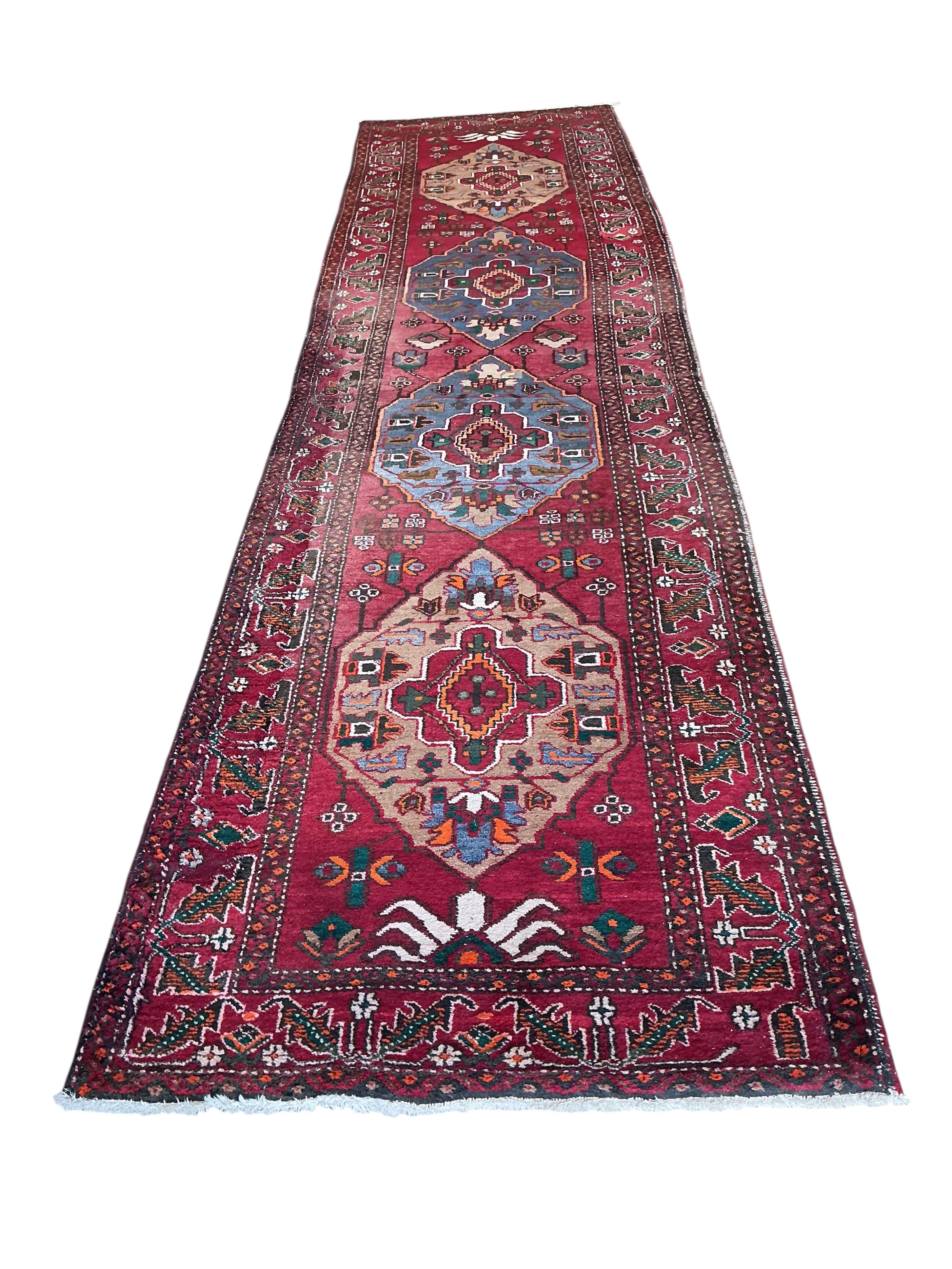 A Caucasian red ground runner, woven with four central elongated octagons, 433 x 113cm